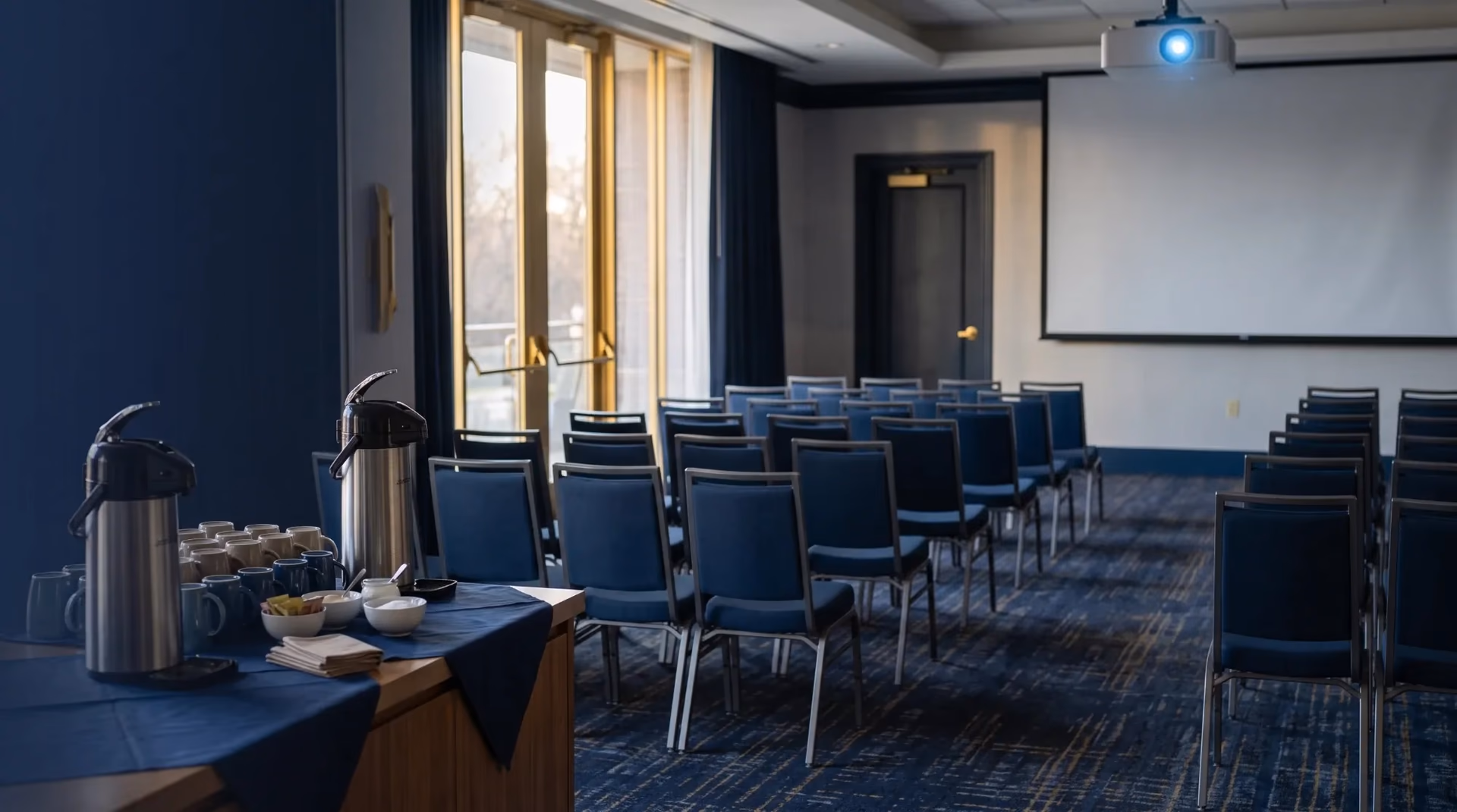 An agency training room set up at dawn with chairs, a lit projector screen, and a coffee station
